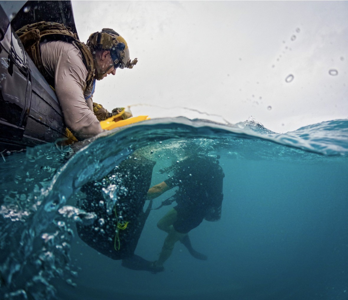 Service members conducting a maritime insertion from a small craft into open water.
