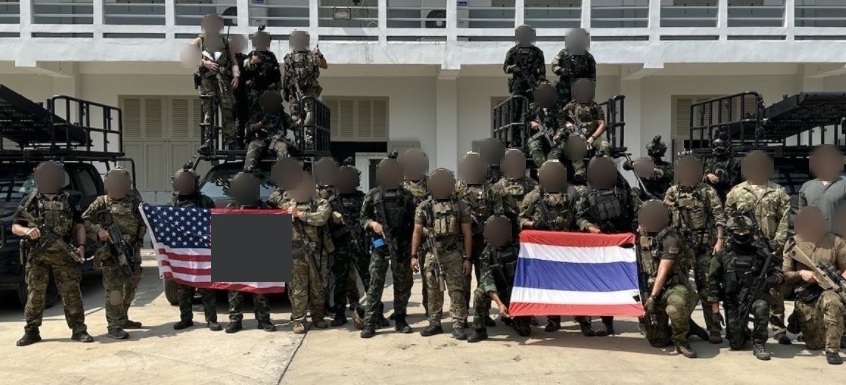 Combined unit formation holding the United States and Thai flags, framed tightly on the group. Faces are obscured and unit insignia redacted.