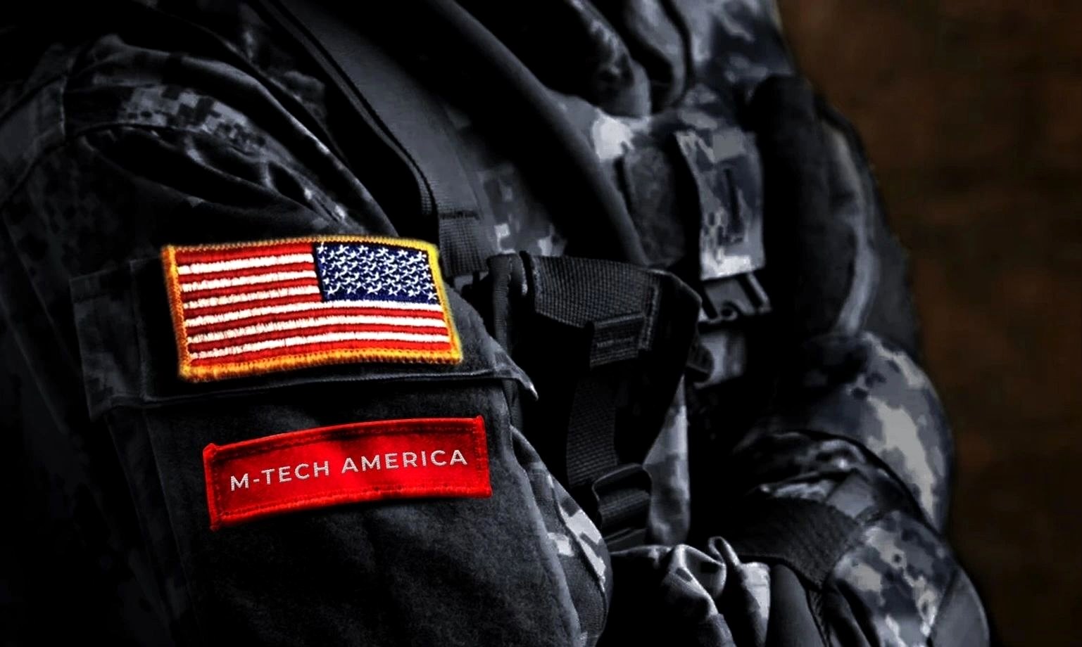 Close-up of a service member's uniform shoulder bearing a United States flag patch and an M-Tech America patch.